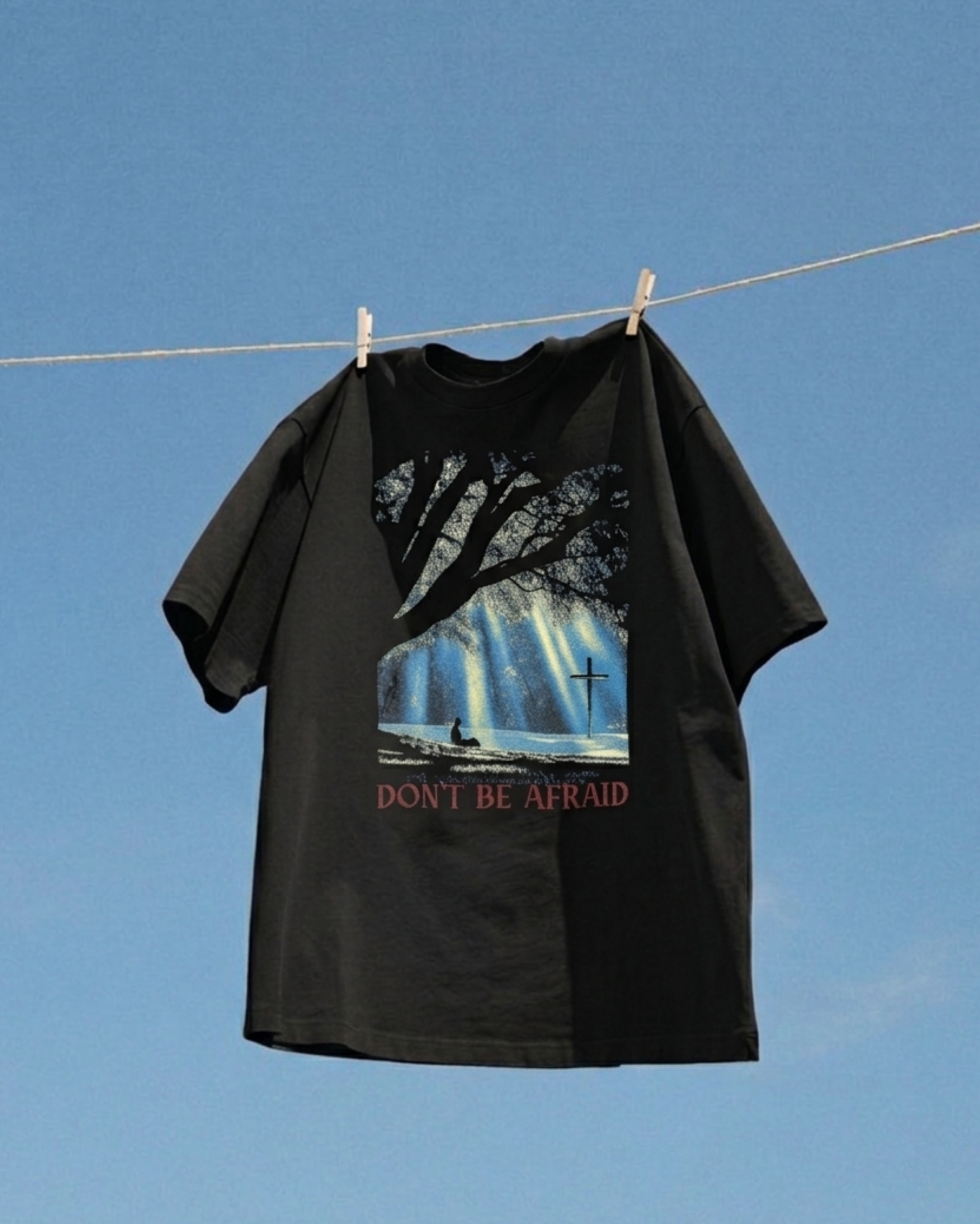 Black Don't Be Afraid graphic tee against a blue sky